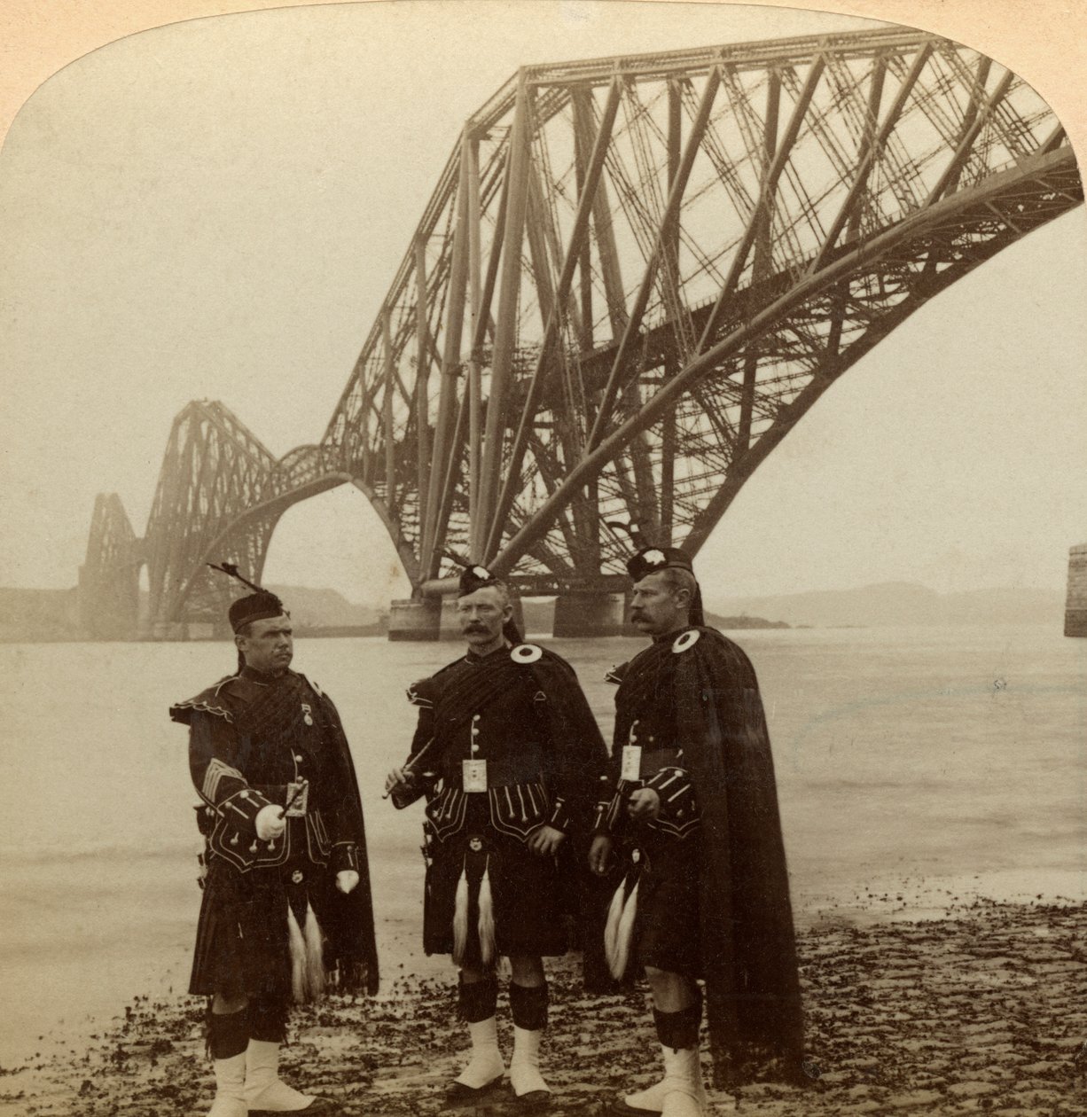 Menn i Highland kler seg foran Forth Bridge, Skottland. av Underwood and Underwood
