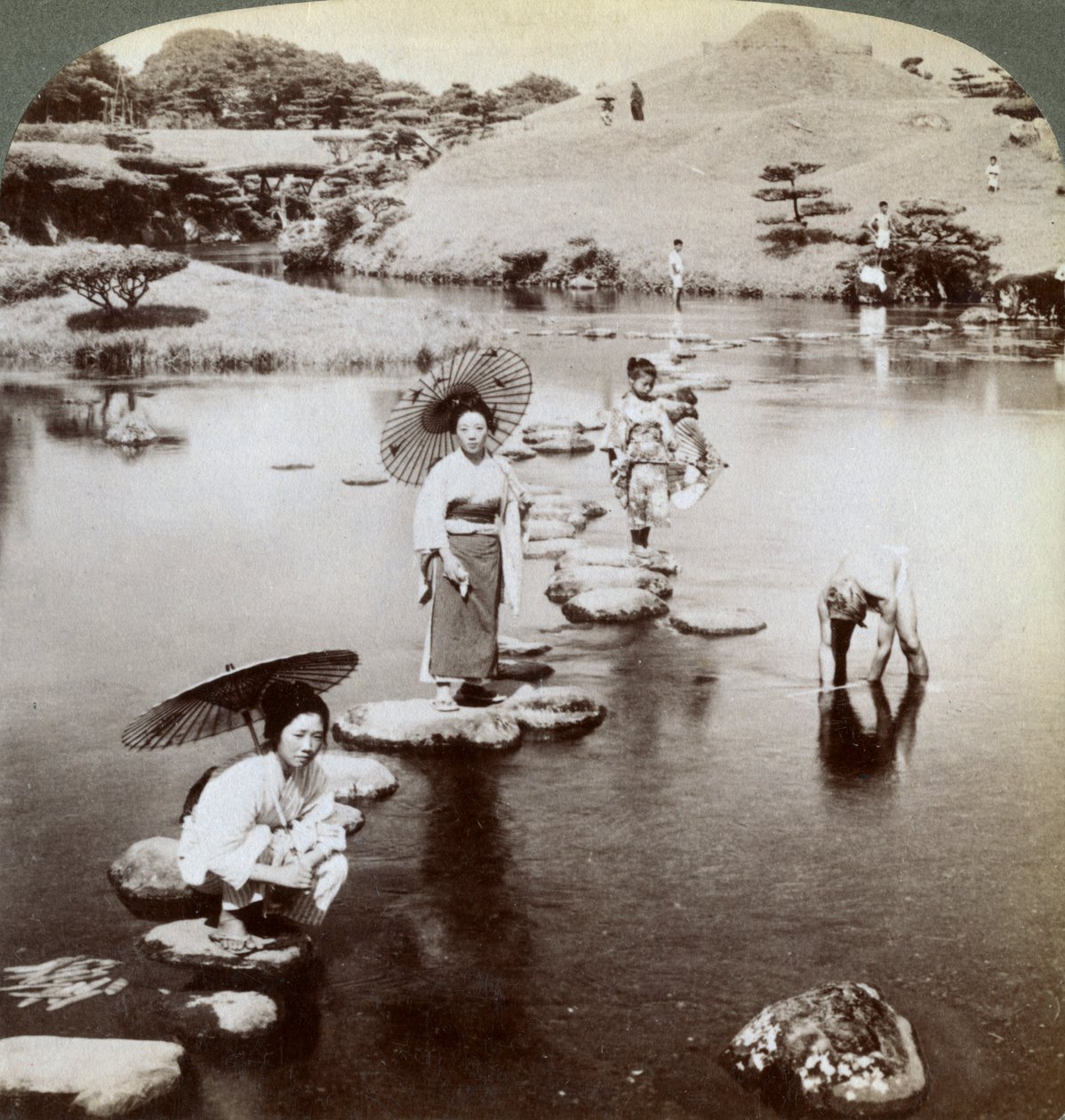 Kvinner krysser innsjøen på trappesteiner, Suizen-ji Garden, Kumamoto, Japan, 1904. av Underwood and Underwood