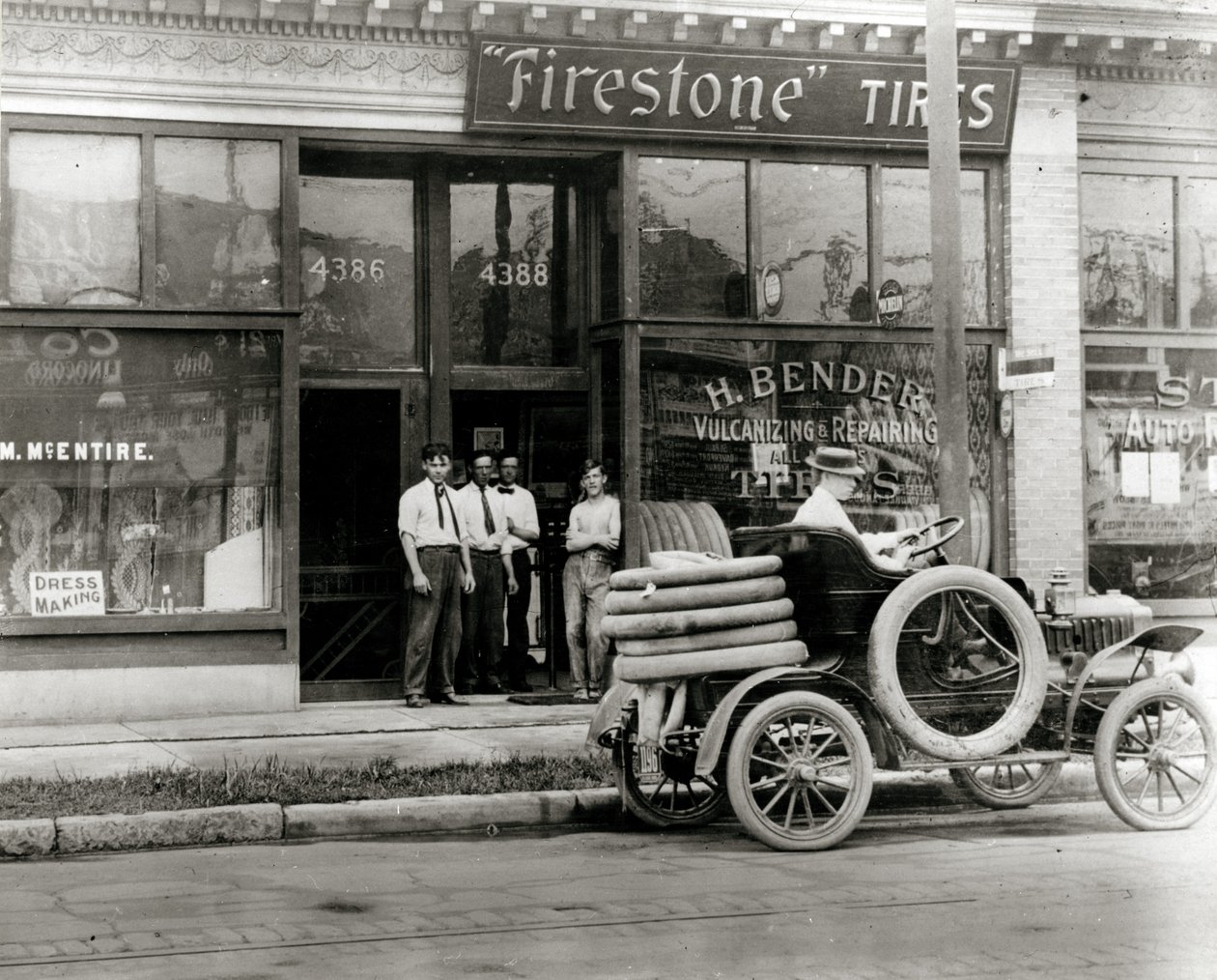Menn og bildekkreparasjonsbil samlet seg utenfor H. Bender Firestone Tire -forhandleren på Olive Street 4388 av Unknown