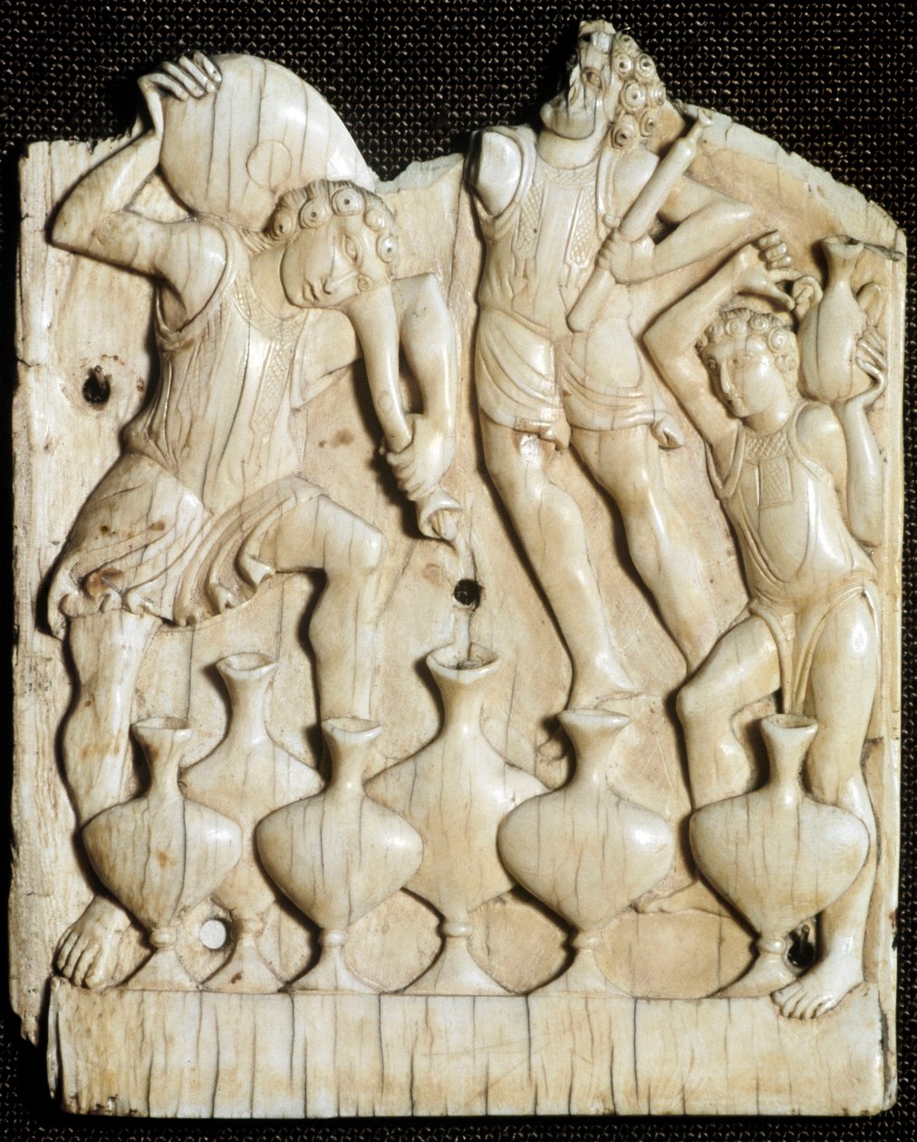 Bryllup i Kana: "" tjenerne fyller med vann seks krukker som Jesus Kristus skal gjøre om til vin""" Utskåret elfenbenstavle. London, Victoria and Albert Museum fra 1000-tallet av Unknown artist