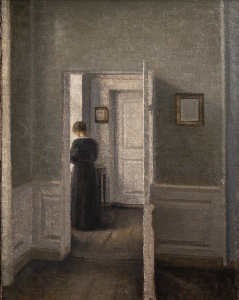 Interiør med en kvinne stående (olje på lerret) av Vilhelm Hammershoi
