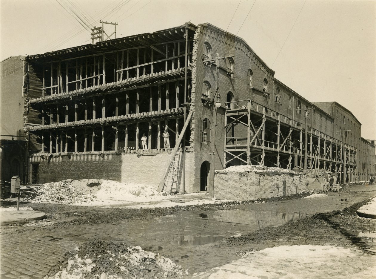 Byggeplass, to menn som står på den åpne siden av lagerbygningen; Robbins und Ripley Engineers and Contractors, 23. mars 1916 av William Davis Hassler