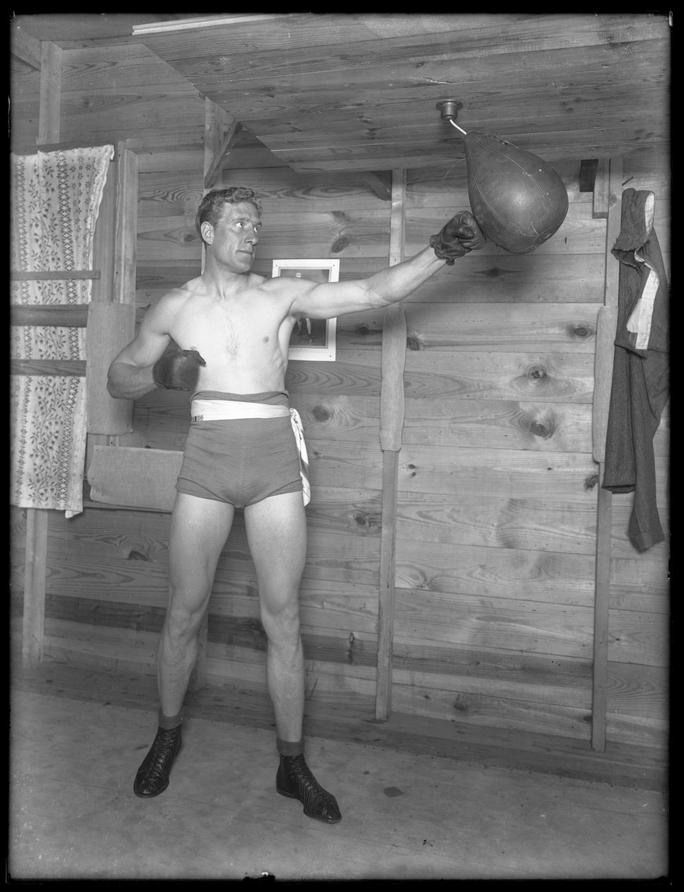 Den engelske bokseren William Thomas Wells (Bombardier Billy Wells), poserer i treningsbukser med speedbag, ca. 1911. av William Davis Hassler
