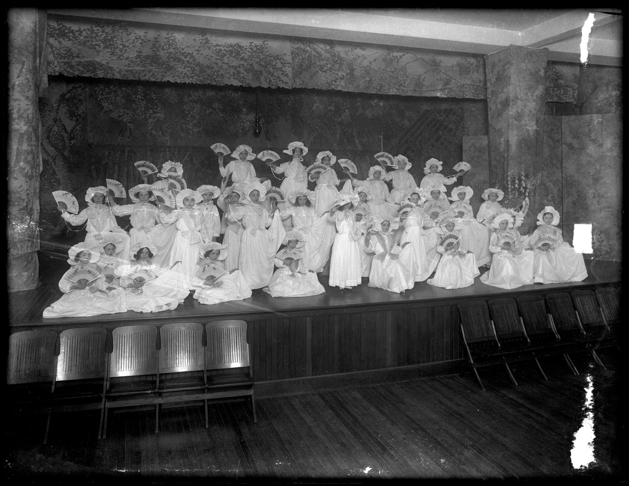 Gruppe med små jenter poserte på en liten scene med fans, sannsynligvis det romersk-katolske orphan asylum, Kingsbridge, Bronx, ca. 1911 av William Davis Hassler