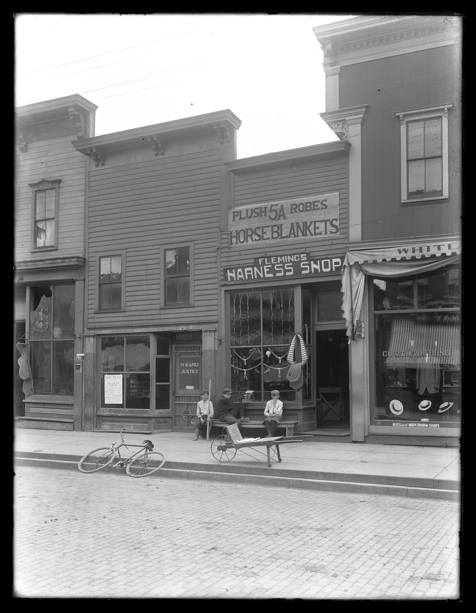 Tre uidentifiserte gutter utenfor Fleming's Harness Shop, muligens Cochranton, Pennsylvania, ca. 1913 av William Davis Hassler