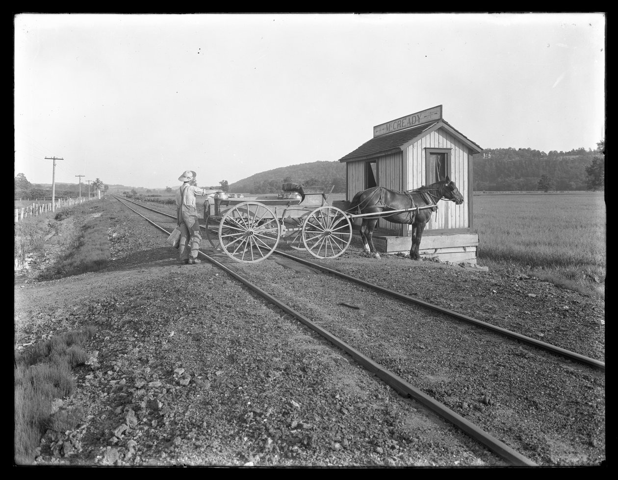 Uidentifisert mann laster melk på hestevogn parkert over jernbanespor utenfor McCready-gården, Pennsylvania, ca. 1913 av William Davis Hassler