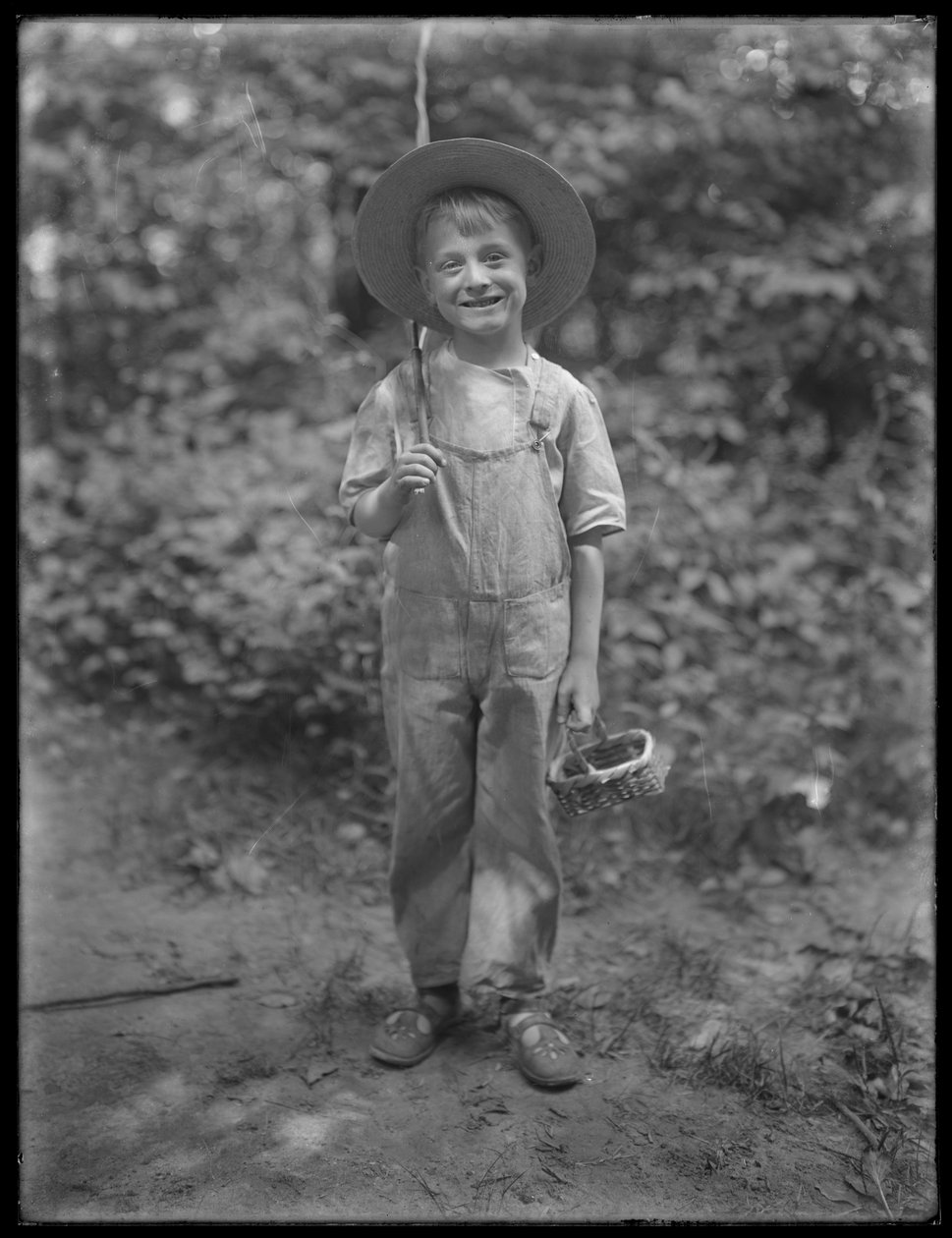 William Gray Hassler i stråhatt og kjeledress, med fiskestang og kurv i skogen, 20. august 1911 av William Davis Hassler