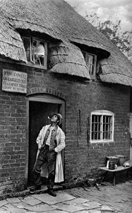 En mann røyker pipe utenfor en butikk, Worcestershire, c1922.
