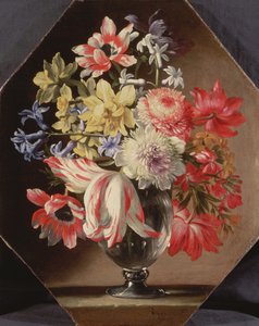 En glassvase med blomster på en steinhylle som inneholder tulipaner, krysantemum, roser og blåklokker