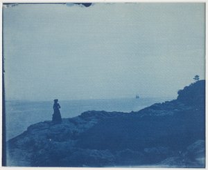 Kvinne som ser på skonnert fra et steinete odde av American Photographer