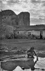 Ung jente leker med en papirbåt i en sølepytt omgitt av gjørme, Venosa, Basilicata, Italia