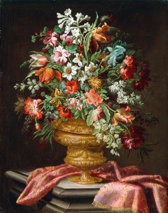 Blomster i en skulpturert urne på en drapert steinsokkel,