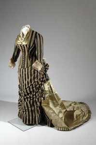 Aftenkjole, ca. 1884 (skrå utsikt fra siden). Silkesateng og kuttet fløyel, blonder, silketråddusker og frynser. Charles Frederick Worth, Frankrike.