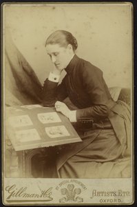 Figur av en kvinne som sitter og inspiserer et fotoalbum av English Photographer