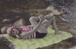 Jente som ligger på håndkle på stranden (farget bilde) av English Photographer