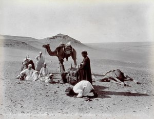 Egyptiske kamelerer under en pause i ørkenen. I forgrunnen ser det ut til at to medlemmer av den lille gruppen ber
