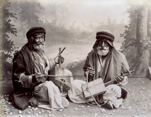 Portrett av to arabiske musikere i ydmyk etnisk kjole. De eldre mennene poserer i studio, sittende på bakken. Bak dem er et bakteppe av et skogkledd landskap av Félix Bonfils