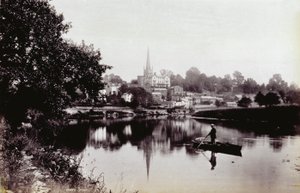 Byen Ross-On-Wye, sett fra en elvebredd. I forgrunnen en mann som står på en robåt av Francis Frith
