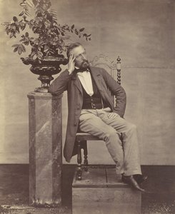 [Mathias Höusermann sittende med albue på pidestall og holder en vase med blomster], 1850-60-tallet. av Franz Antoine