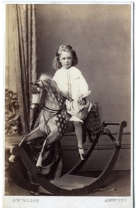 Ung jente sitter på en gyngehest, 1860-tallet (albumintrykk)