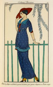 Robe de plage en foulard garni de tussor gros grain chapeau en Suède rouge. Kostymer Parisiens nr.15. Kvinne iført en strandkjole og et råsilkeskjerf trimmet med grosgrain i flekkete blått og en rød lue. av Georges Barbier