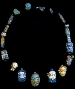 Halskjede i glasspasta med anheng som viser skjeggete hoder, opprinnelig fra Olbia, nå bevart ved National Archaeological Museum of Cagliari