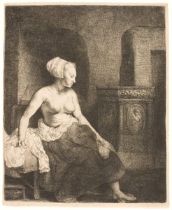 Kvinne som sitter halvkledd ved siden av en komfyr av Rembrandt van Rijn
