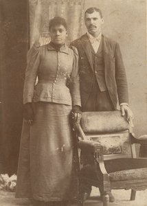 Fotografi av et afroamerikansk par som står bak en stol, ca. 1890. av Schmitz Studio