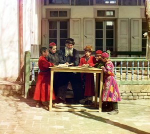 En gruppe jødiske barn med en lærer på et bord foran et hus, Samarkand, det russiske imperiet, mellom 1905 og 1915
