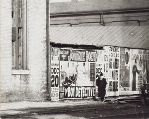 En mann går forbi en vegg med plakatannonser, inkludert en for Johnnie Hoey The Boy Detective som spiller på Havlins teater på 600 Walnut Street. av Unbekannt