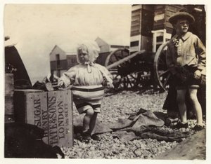 To barn ved bademaskiner, c 1895, Et øyeblikksbilde av to barn ved sjøen, stående blant en gruppe bademaskiner på stranden av Unbekannt