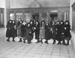 USA: ca. 1926 En gruppe kvinner som står ved «Savings»-kassevinduene i en bank. (s/hvitt bilde) av Unbekannt