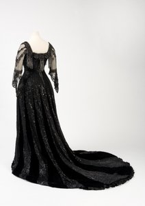 Sort kveldskjole i full lengde båret av dronning Alexandra, med dekorasjon av perler og paljetter og inkorporert dronning Alexandras signaturteip i svart silke og gull, laget av Barolet fra Knightsbridge, London 1908-1910 (silke og fløyel) av Unbekannt