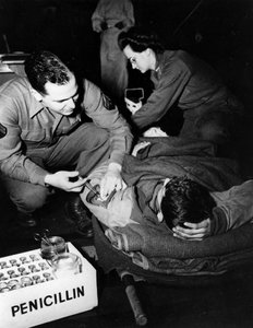 Andre verdenskrig (1939–1945) - Andre verdenskrig (2 eller 2): Luxembourg februar 1945: På et evakueringssykehus fra den amerikanske hæren administrerer en medisiner (sykepleier) penicillin til en skadet soldat for å unngå infeksjon mens en sykepleier forb av Unbekannt