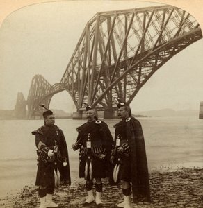 Menn i Highland kler seg foran Forth Bridge, Skottland. av Underwood and Underwood