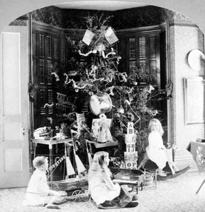 Barn samlet ved foten av treet omgitt av gaver på julemorgen. av Unknown photographer