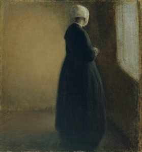 En gammel kvinne som står ved et vindu