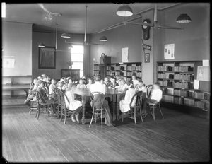 Barn lytter til en kvinne på lesesalen til en uidentifisert filial av Queens Borough Public Library, ca. 1910 (s/hvitt-bilde) av William Davis Hassler