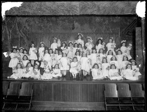 En gruppe små jenter poserte på en liten scene med dukker, sannsynligvis det romersk-katolske orphan asylum, Kingsbridge, Bronx, ca. 1911