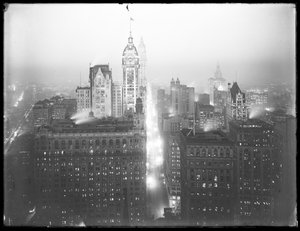 Høyvinklet tåkete nattutsikt over nedre Manhattan ser nordover, med Singer Building, Woolworth Building og Municipal Building synlig, ca. 1913 av William Davis Hassler