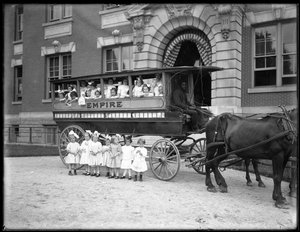 Små jenter poserer i og foran en hestevogn, foran en uidentifisert bygning, sannsynligvis det romersk-katolske orphan asylum, Kingsbridge, Bronx, ca. 1910 av William Davis Hassler