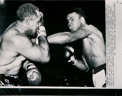 Unge Cassius Clay scorer med venstre mot veteranen Archie Moore i første runde av kampen i Los Angeles av American Photographer