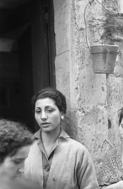 KVINNER PÅ DØRSTALLEN TIL HUSET av Ando Gilardi