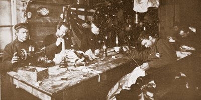 I hytta midtvinteren drev mennene med å sy pelsverk til klær som skulle brukes til aking på våren, pub. London 1907 (s/hvitt-bilde) av Anthony Fiala
