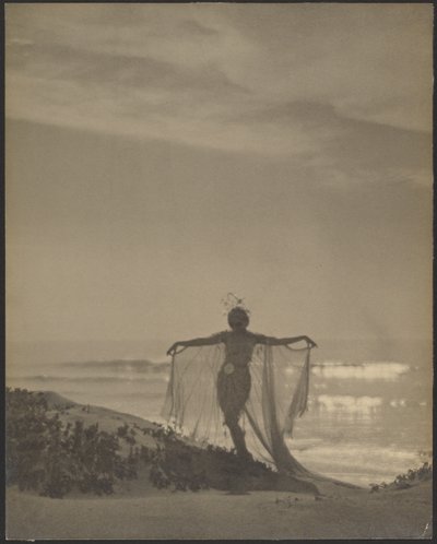 [Bakfrabilde av en danser iført et gjennomsiktig kostyme på stranden] av Arthur F. Kales