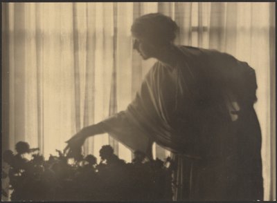[Kvinne steller blomster inne i leiligheten sin] av Arthur F. Kales