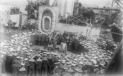 Sjømenn flokker seg rundt Australias statsminister The Hon William Morris (Billy) Hughes mens han henvender seg til dem på dekket til HMAS Australia ved verftet i Devon, England, 21. mai 1916 av Australian Photographer