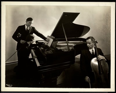 Blind kvinne, Miss Harding, ved pianoet og instruerte to blinde menn på fiolin og cello, 1936 (sølv gelatintrykk) av Byron Company