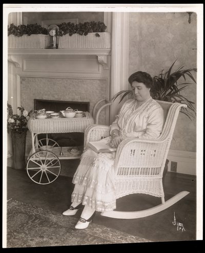 Mrs. Howard satt med en bok i en gyngestol hjemme hos henne på 200, 5th Avenue, New York, 1915-6 (sølv gelatintrykk) av Byron Company