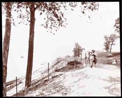 Utsikt over en gutt med kikkert som ser mot Hudson River fra Riverside Park, New York (sølv gelatintrykk) av Byron Company